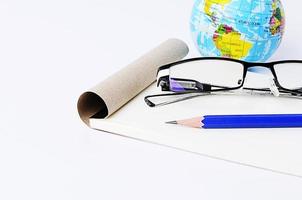 close up of Blue pencil with eyeglasses and notepad paper with earth ball photo