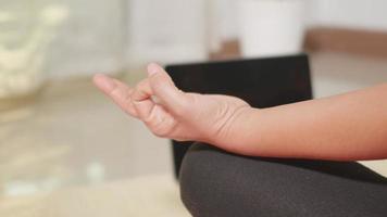 polainas de mujer joven asiática practicando yoga en casa sentado en posición de loto en la estera de yoga para el equilibrio, mujer trabajando en casa en la sala de estar. estilo de vida deporte concepto de meditación saludable, cámara lenta video