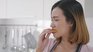 portret aziatische jonge gelukkige mooie vrouw op keuken ze bijt naar het eten van verse citroen keuken. vrouwelijke emotie die een zeer zure uitdrukking maakt. gezond levensstijlconcept. slow motion video