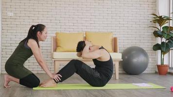 gelukkige Aziatische familie paar man en vrouw gezonde trainer training thuis in de woonkamer. fit man levensstijl doet sit-up fitness oefening thuis op de vloer met vriendin ondersteuning helpen vriendje video