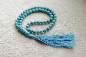 Long blue turquoise prayer beads for praying on light background photo