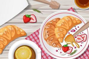 Croissant with strawberry and a cup of lemon tea on the table vector