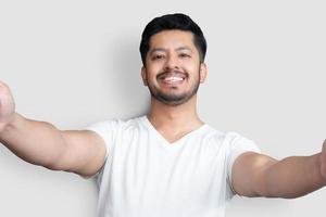 primer plano foto asombroso él él su juventud asiático paquistaní apariencia perfecta persona tranquila hacer tomar selfies sincero sonrisa vestir camiseta blanca aislado fondo blanco
