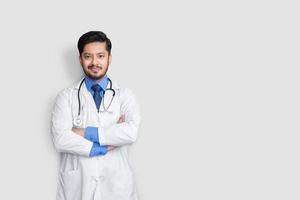 Retrato de médico masculino sonriendo con estetoscopio y cruz de brazo aislado sobre fondo blanco. concepto de seguro médico. foto