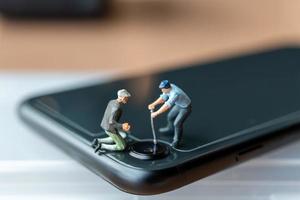 Miniature people Worker with tools repairing mobile phone photo