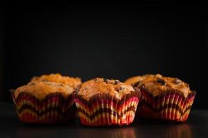 Muffins on a black background. Sweet homemade raisin cakes. photo
