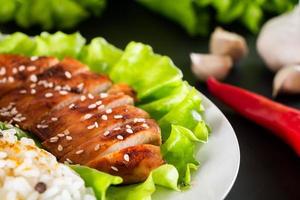 comida casera - pollo teriyaki con arroz blanco y pimienta sobre un fondo negro. foto