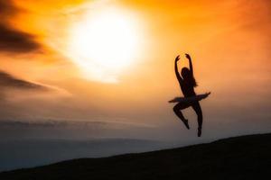 Ballerina silhouette, dancing alone in nature in the mountains at sunset photo