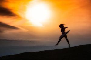 Ballerina silhouette, dancing alone in nature in the mountains at sunset photo