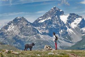 una niña con su gran perro negro en la montaña disfruta de la vista foto