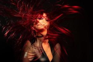 A girl on a black background with double exposure with red hair in the wind photo