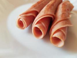 Three rolls of ham on the white plate photo