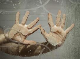 Hand on wet window photo