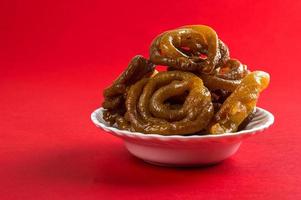 Indian sweet jalebi, indian dessert jalebi or imarti or imarati or jilbi on red background photo