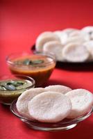 Idli with Sambar and coconut chutney on red background, Indian Dish south Indian favourite food rava idli or semolina idly or rava idly, served with sambar and green chutney. photo