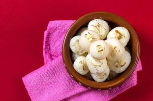 Indian Sweet or Dessert - Rasgulla, Famous Bengali sweet in clay bowl with napkin on Red Background photo