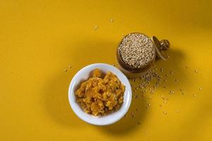 Sesame Seeds in clay pot with Jaggery in bowl on yellow background photo