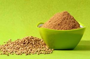Coriander seeds and Powdered coriander in green container on green background photo