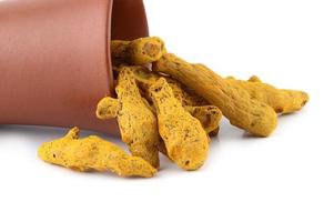 Dry Turmeric roots or barks in clay pot isolated on white background photo