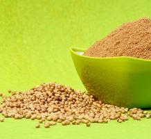 Coriander seeds and Powdered coriander in green container on green background photo