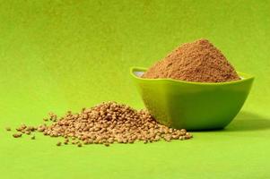 Coriander seeds and Powdered coriander in green container on green background photo