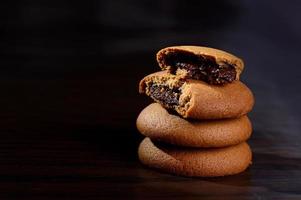 galletas rellenas de crema de chocolate. galletas de crema de chocolate. Galletas de chocolate marrón con relleno de crema sobre fondo negro. foto