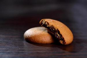 galletas rellenas de crema de chocolate. galletas de crema de chocolate. Galletas de chocolate marrón con relleno de crema sobre fondo negro. foto