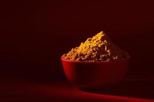 Dry Turmeric powder and roots or barks in red bowl on red background photo