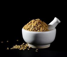 Coriander Powder and seeds with mortar and pestle on black background. photo