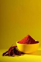 chili powder in yellow bowl on yellow background. Red chilly pepper photo