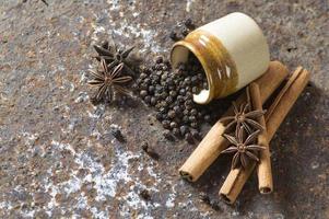 especias y hierbas. ingredientes de la comida y la cocina. palitos de canela, estrellas de anís, granos de pimienta negra sobre fondo de textura foto