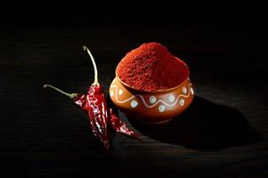 chilly powder in clay pot with red chilly, dried chillies on wooden background photo