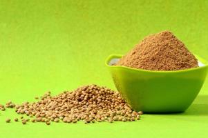 Coriander seeds and Powdered coriander in green container on green background photo