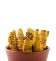Dry Turmeric roots or barks in clay pot isolated on white background photo