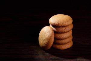 Galletas - Pila de deliciosas galletas de crema rellenas con crema de chocolate sobre fondo negro foto