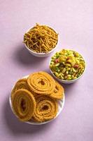 Indian Snack Chakli, chakali or Murukku and Besan Gram flour Sev and chivada or chiwada on pink background. Diwali Food photo