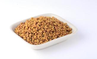 Fenugreek seeds in white plate isolated on white background photo