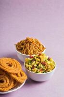 Indian Snack Chakli, chakali or Murukku and Besan Gram flour Sev and chivada or chiwada on pink background. Diwali Food photo