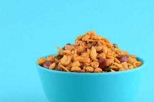 Indian Snacks Mixture roasted nuts with salt pepper masala, pulses, channa masala dal green peas in blue bowl in photo