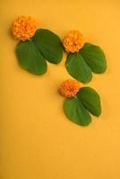 Indian Festival Dussehra, showing golden leaf Bauhinia racemosa and marigold flowers on a yellow background. photo