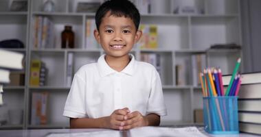 Boy sitting on desk and waving hands gesturing hello or goodbye. video