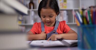 Asian little girl practicing reading at the desk at classroom. video