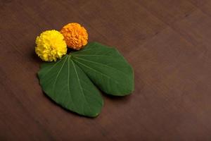 Indian Festival Dussehra, showing golden leaf Bauhinia racemosa and marigold flowers on a Brown background. photo