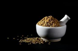 Coriander Powder and seeds with mortar and pestle on black background. photo