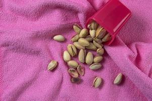 Pistachios in container on pink background photo