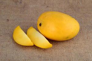 Fruta de mango con rodaja sobre fondo de tela de saco foto