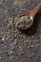 Cumin seeds in wooden spoon on a textured background photo