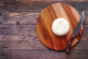 top view of round shape fresh cheese on chopping board photo