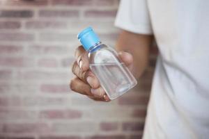 hand holding sanitizer liquid against brick background photo