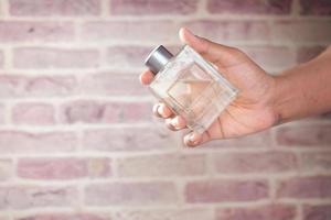 hand hold perfume against brick background photo